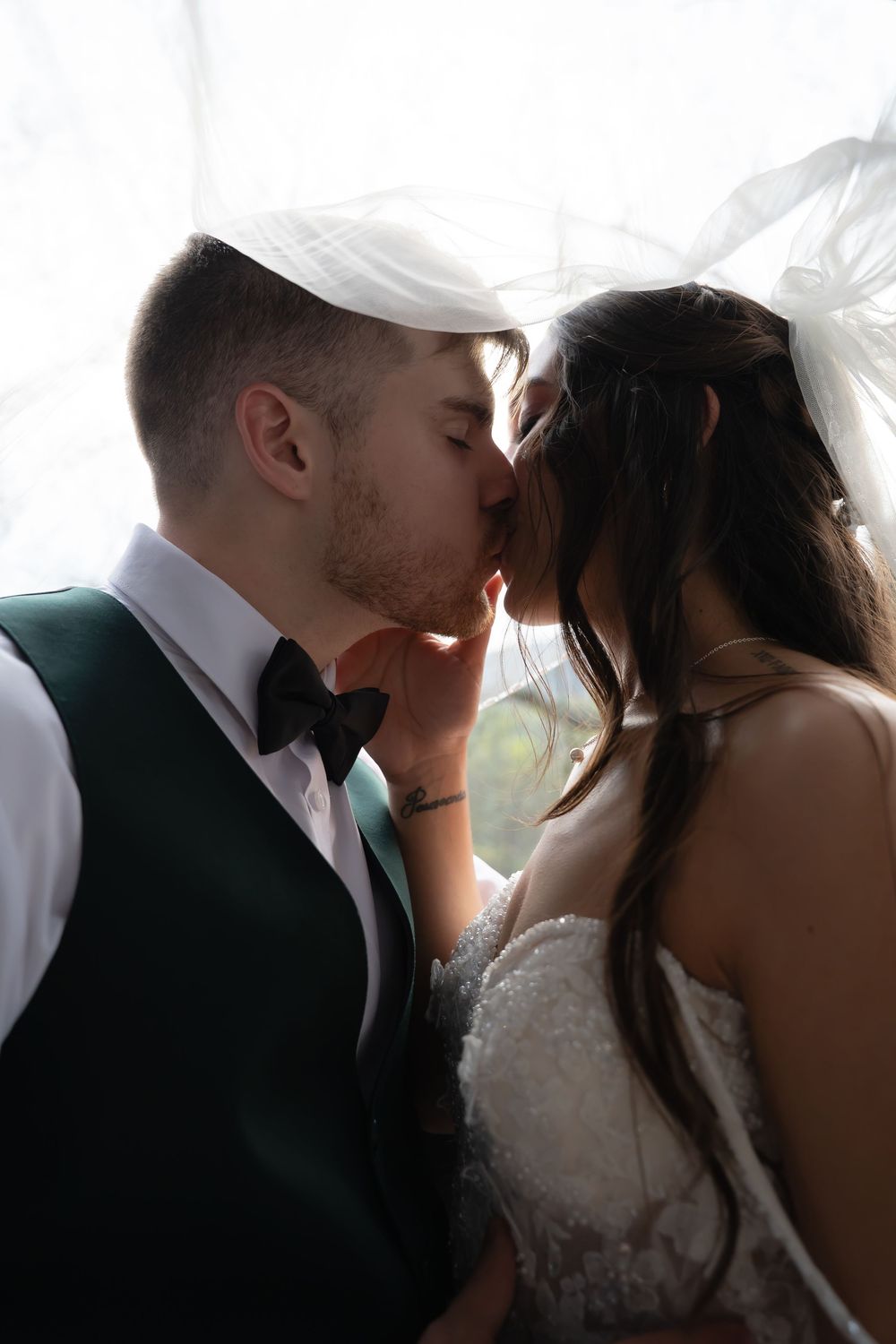 Romantic wedding portraits captured in soft lighting with white bridal gown details.
