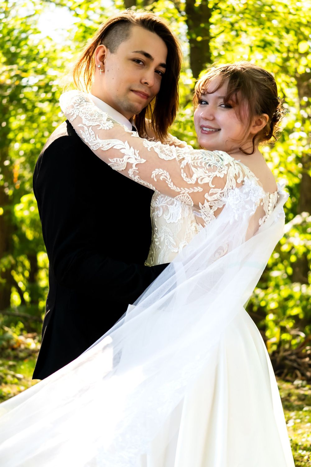 A couple dances in a sunlit forest setting during their romantic wedding photoshoot.
