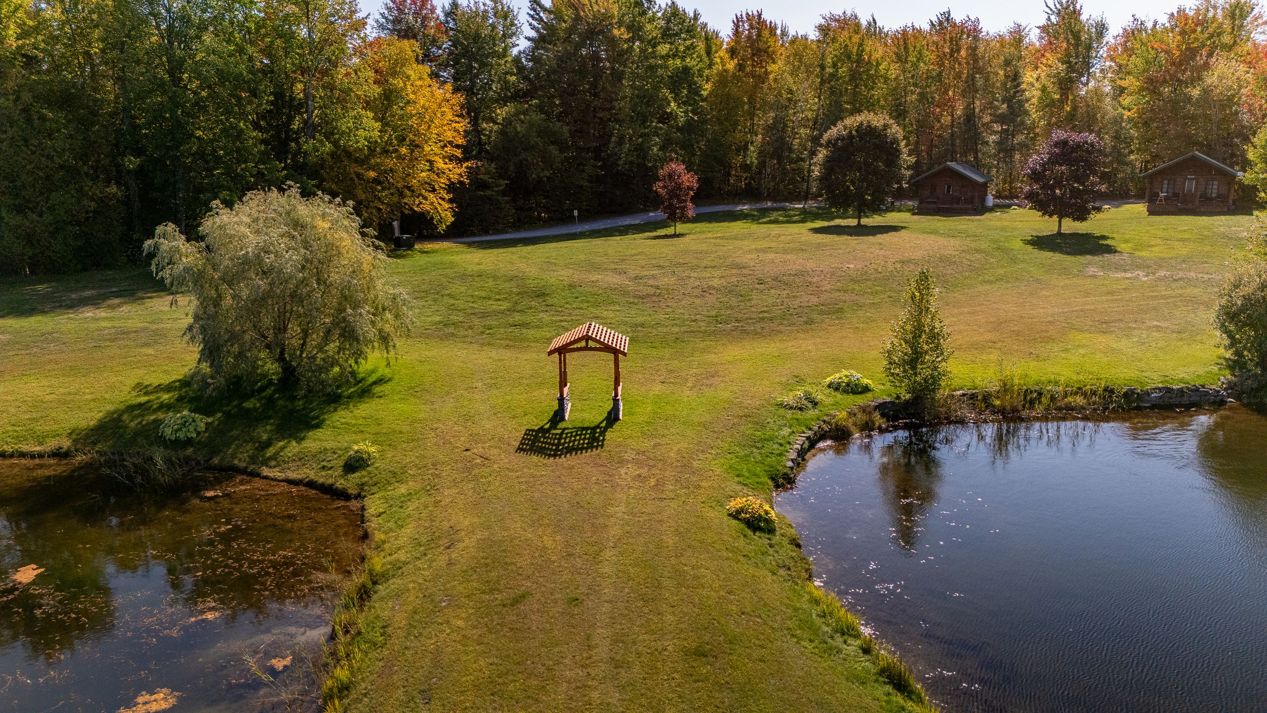 Aerial drone view of a wooden wedding arch beside a lake at Domaine Labrador, Clarence Creek Ontario.