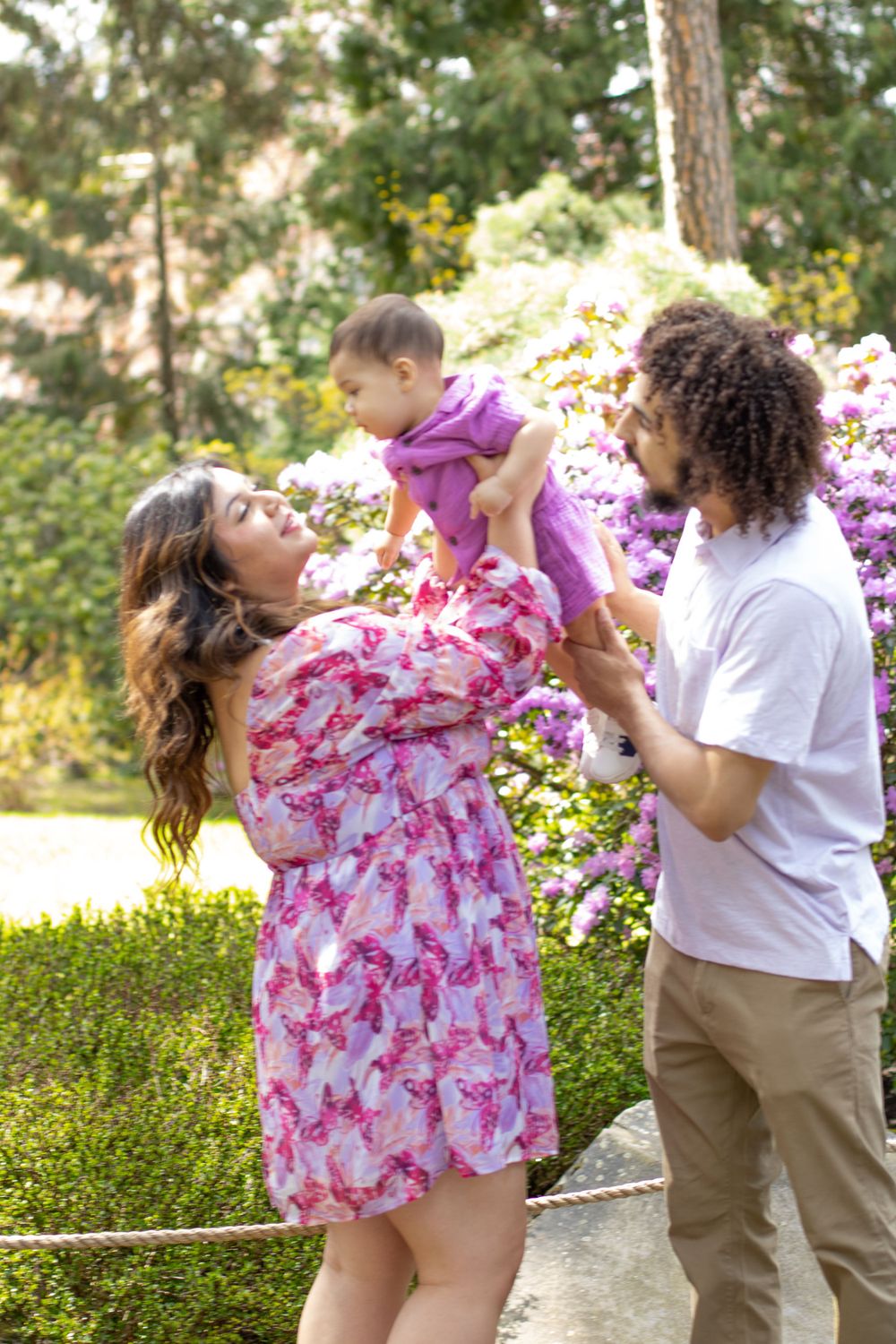 Family plays together in garden setting with blooming flowers and greenery.