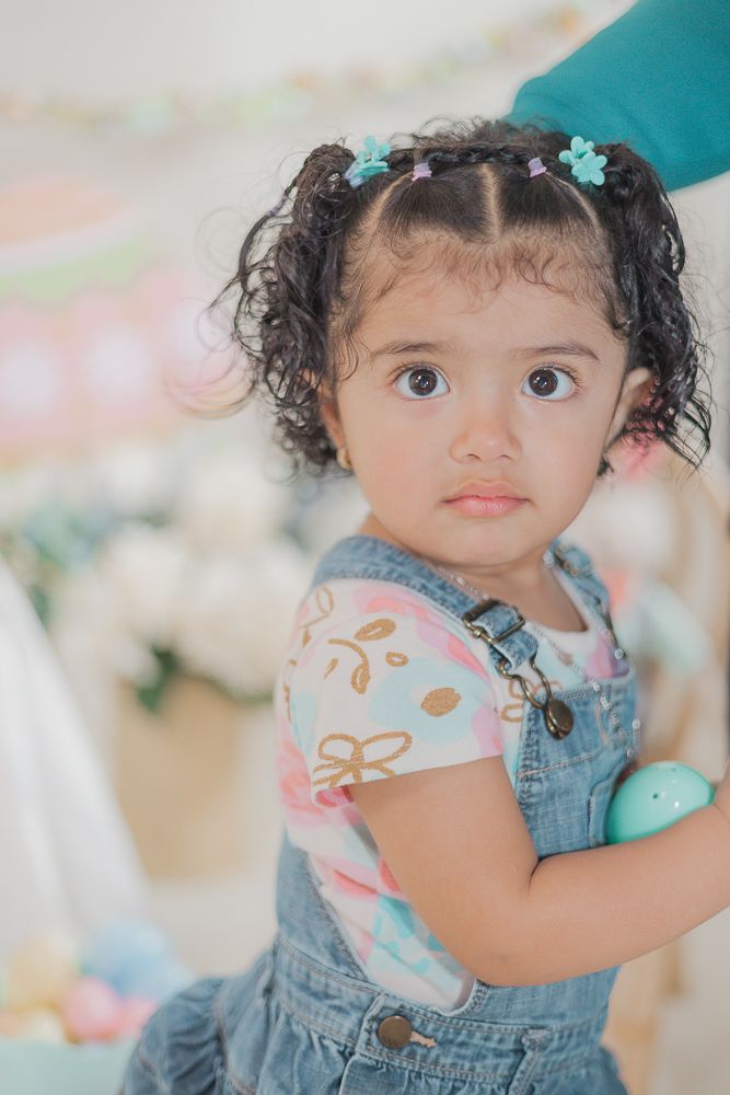 Sweet portrait in denim overalls with floral top and tiny blue hair clips.