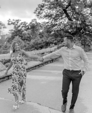 A couple dances playfully on a stone path in a romantic black and white photo.