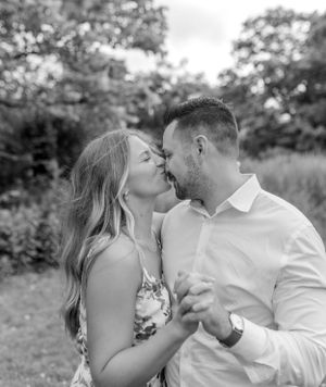 An intimate black and white portrait of a couple sharing a romantic moment in a garden setting.