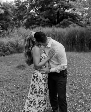A romantic black and white photo of a couple embracing in a natural garden setting.