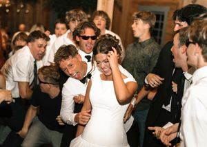 Wedding celebration inside venue with guests dancing and enjoying festivities in formal attire.