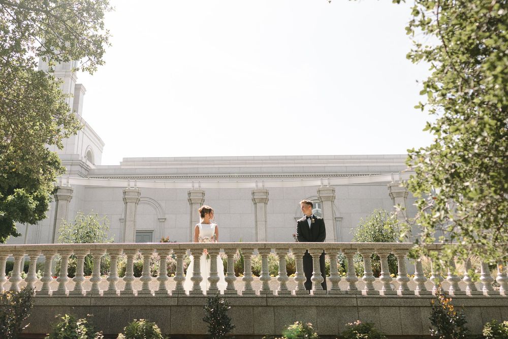 A white balustrade railing stretches along a path with trees and greenery visible in the background on a misty day.
