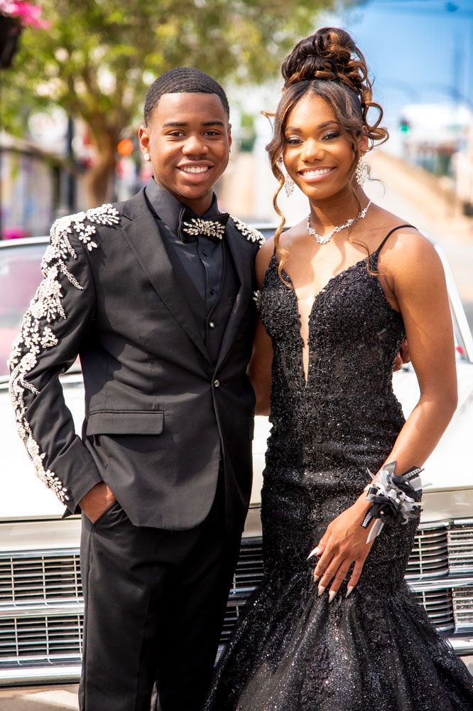 Formal couple poses in black tie attire with sparkly embellishments.