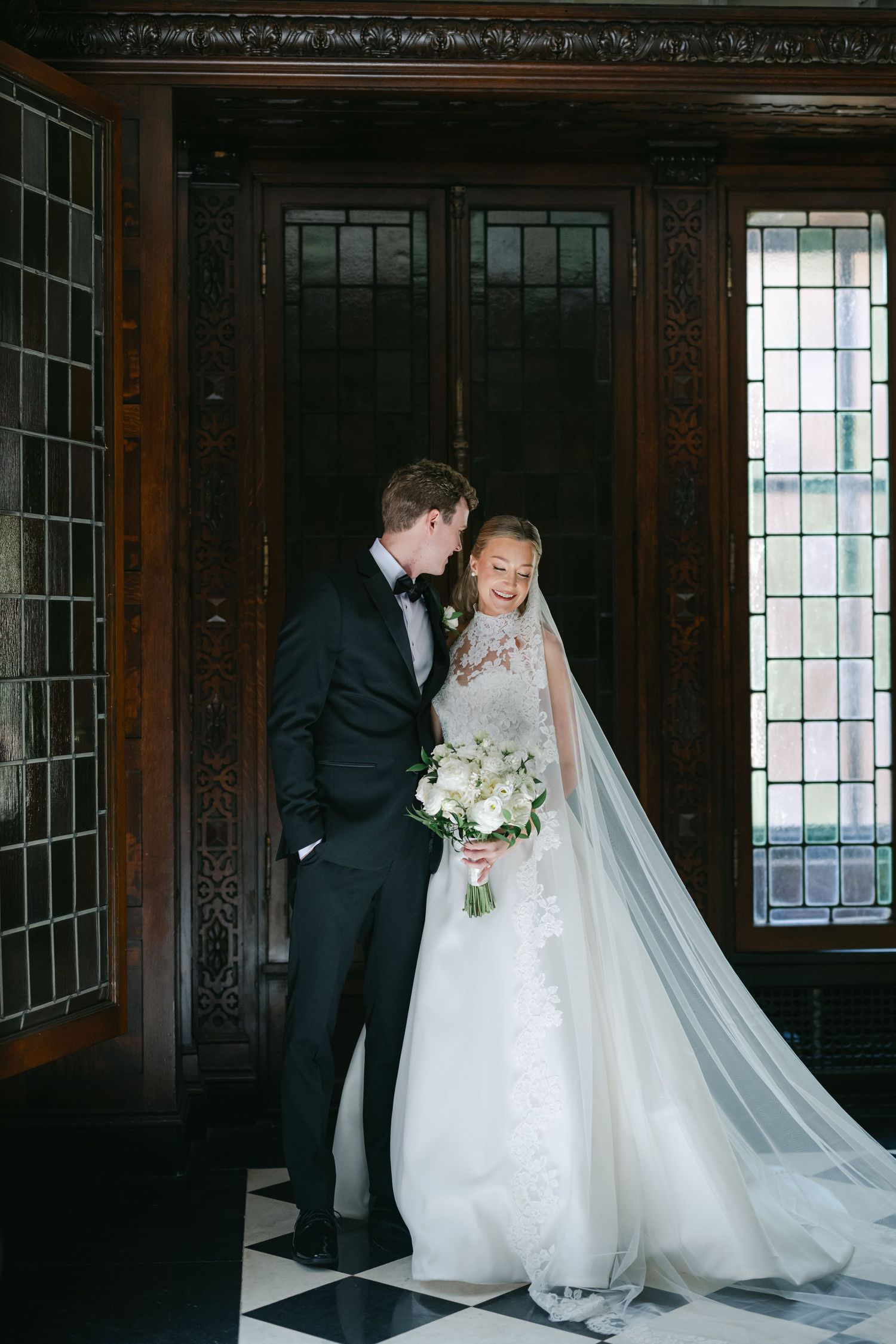 Bride and groom share a romantic kiss in an elegant venue with checkered floors. - The Blackstone Hotel Wedding