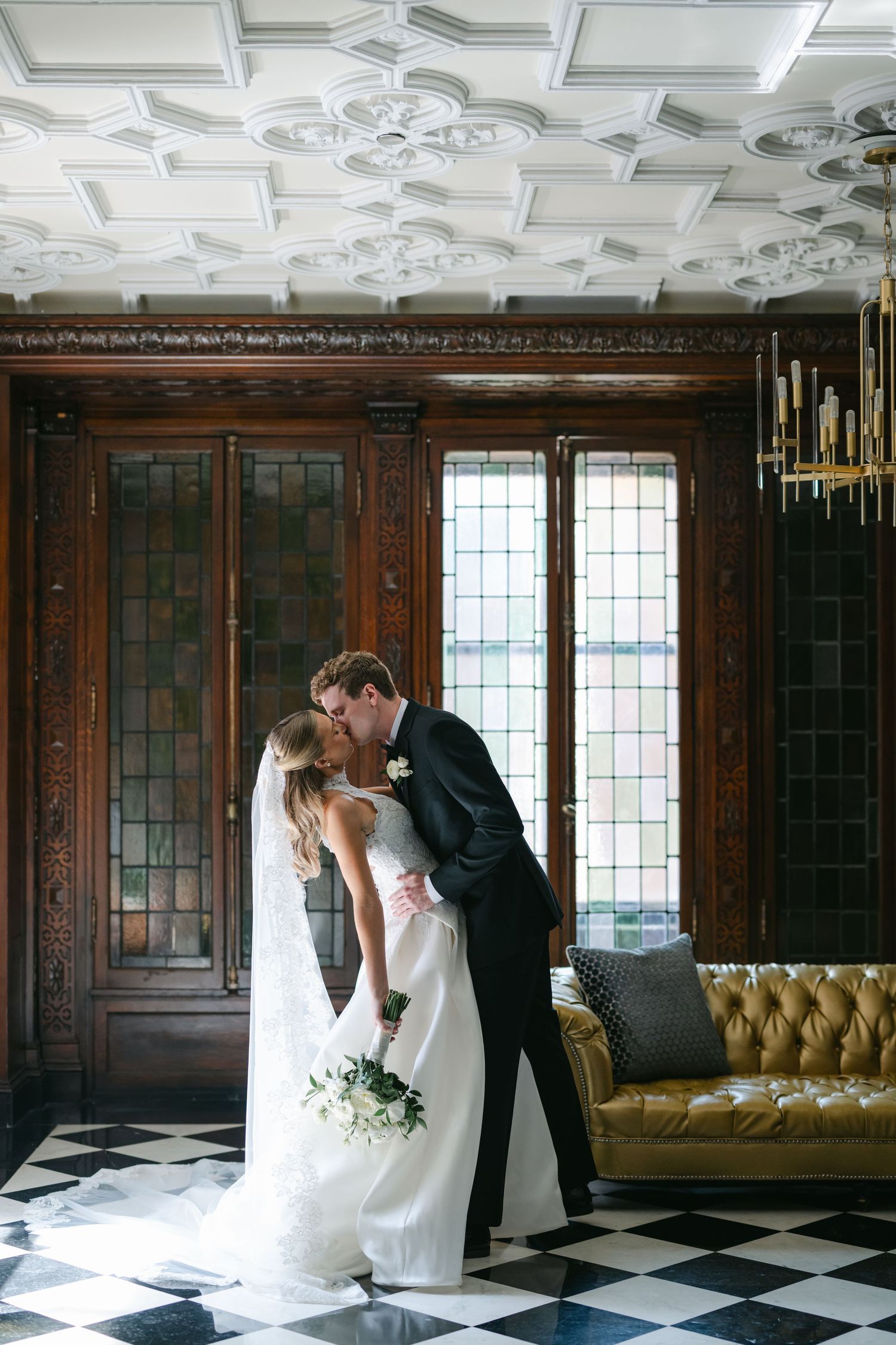 Bride and groom share a romantic kiss in an elegant venue with checkered floors. - The Blackstone Hotel Wedding