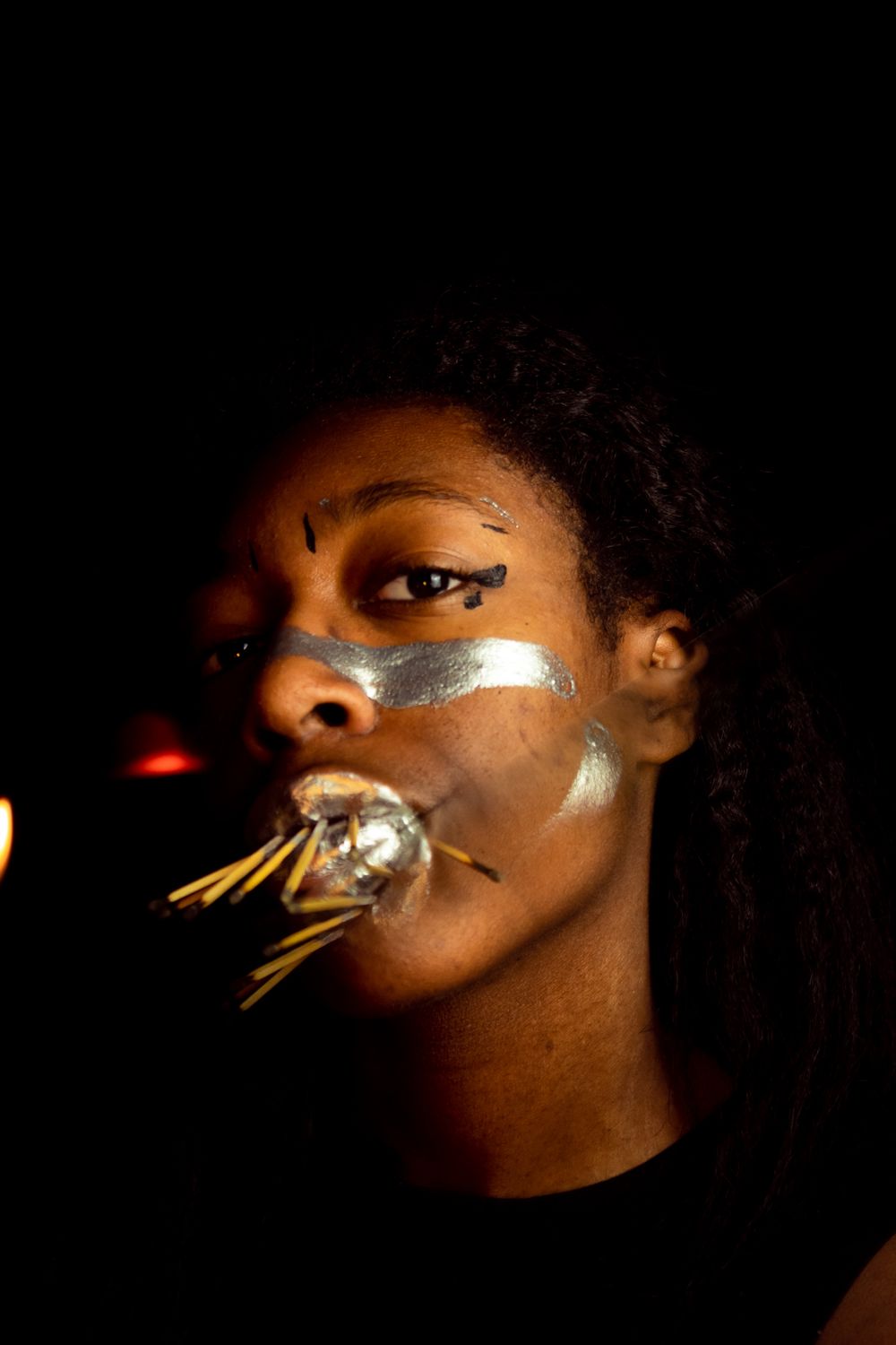 A person with matches in their mouth, fire on the left side, and reflection of the matches in the middle.