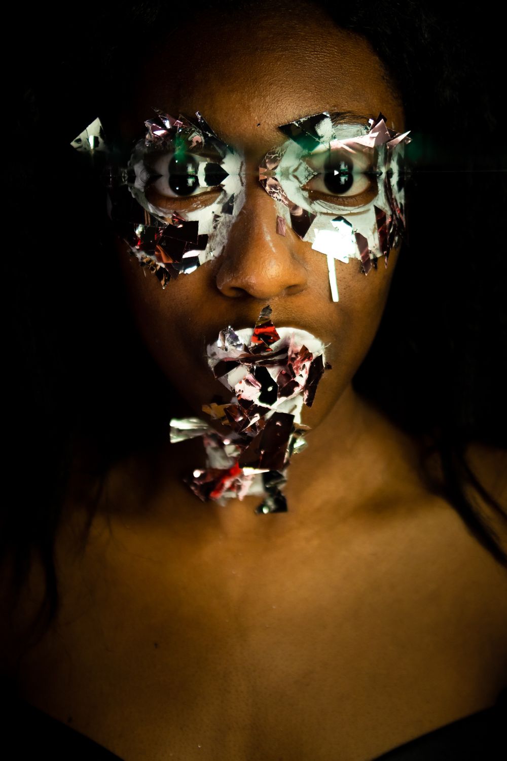 A person with paint and big glitter on their face, a small reflection near the top of the eyes.