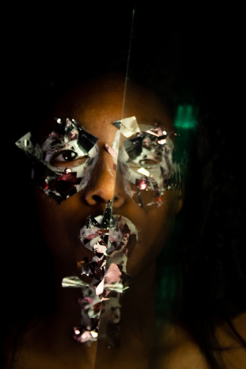 A person with paint and big glitter on their face, a clear object blocking half of the face.