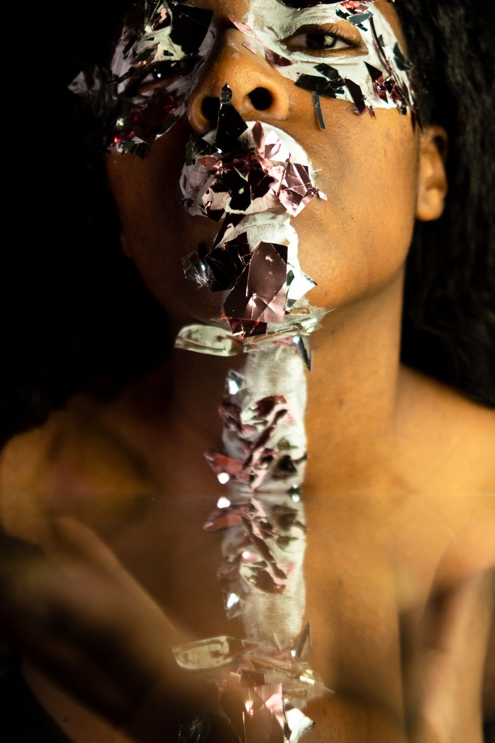 A person with paint and big glitter on their face, a small reflection near the bottom.