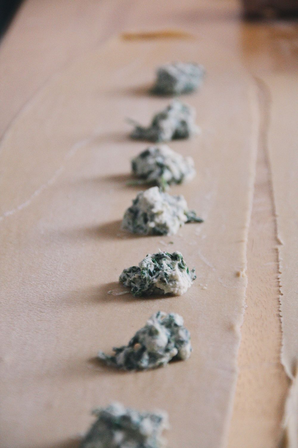 Small portions of green filling arranged in a line on brown parchment paper.