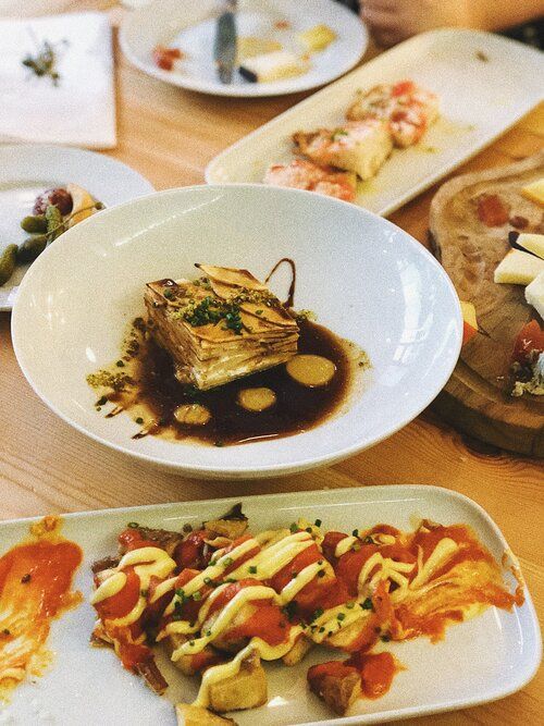 Variety of plated dishes with sauces and garnishes in an elegant presentation.