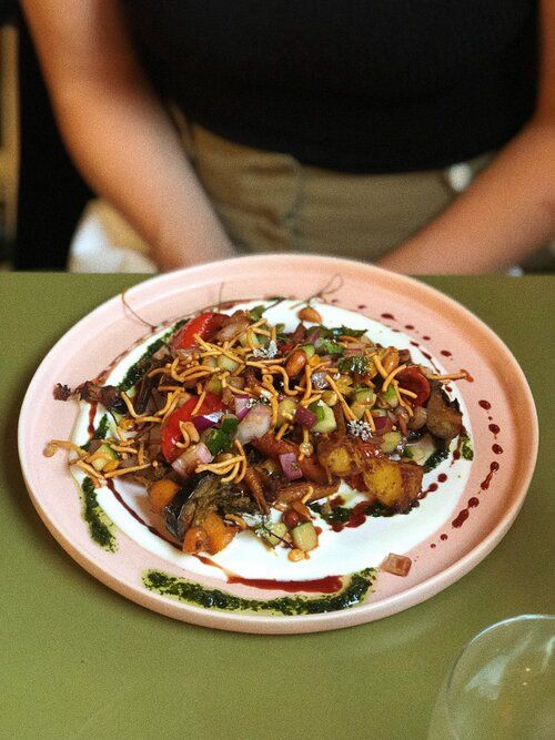 Beautifully plated gourmet dish with vegetables and garnishes on a white ceramic plate.