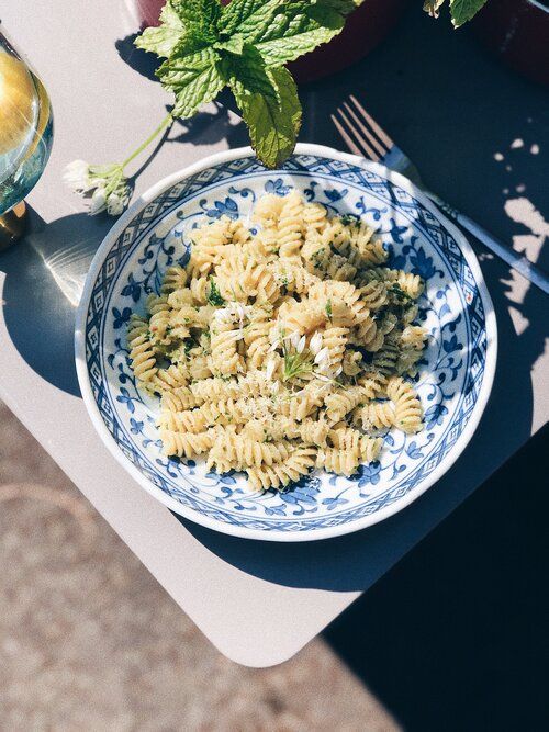 Pasta salad with fresh herbs served on a blue and white patterned plate.