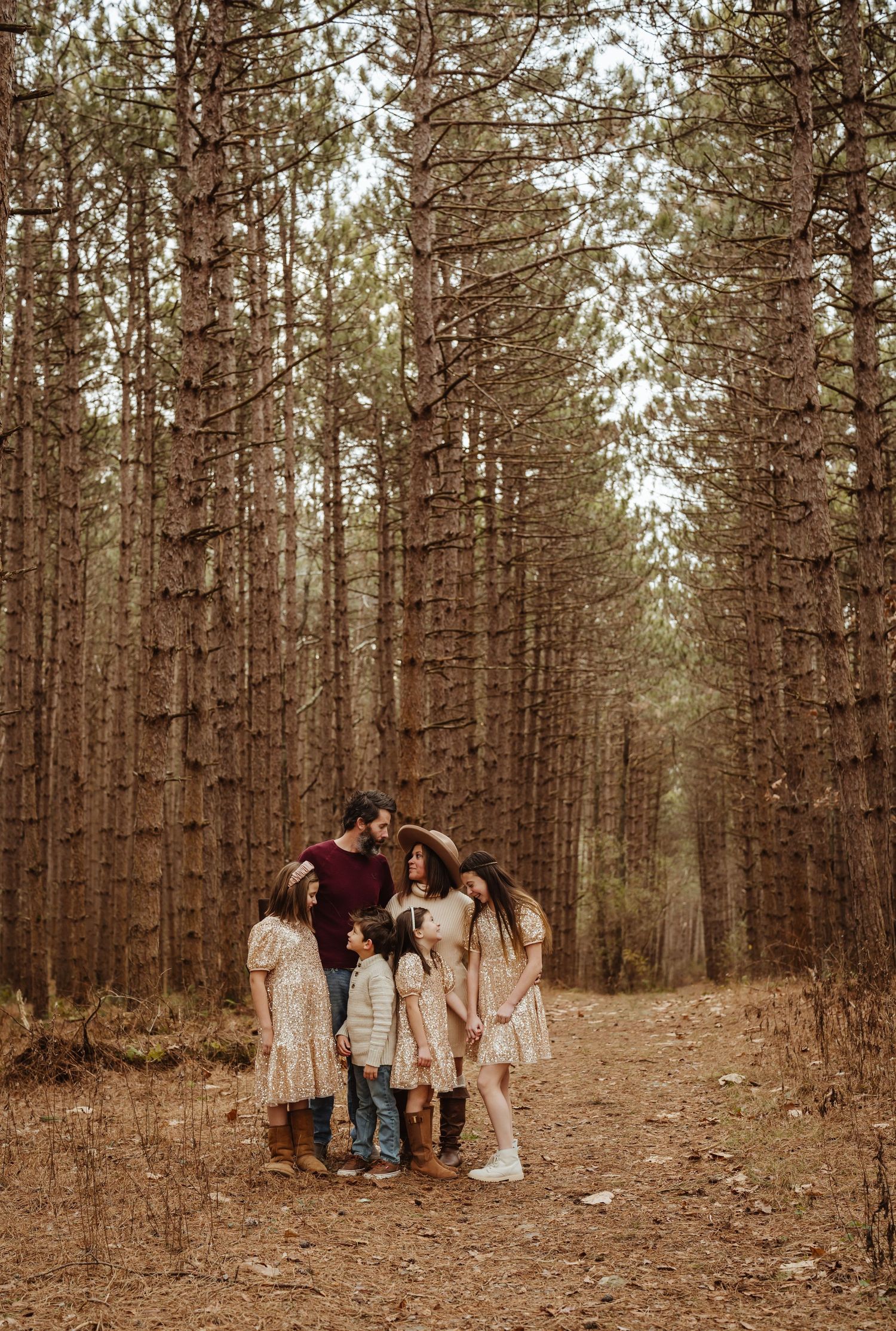 Family standing together on path through tall pine forest.