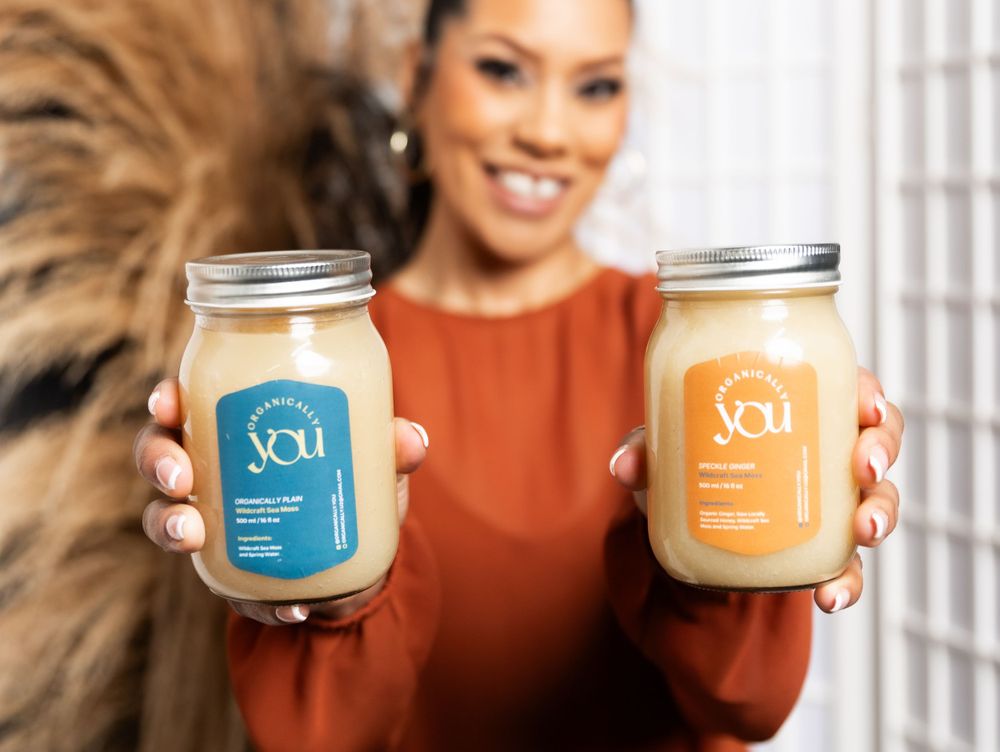 Person holding two glass jars of YOU branded smoothies.