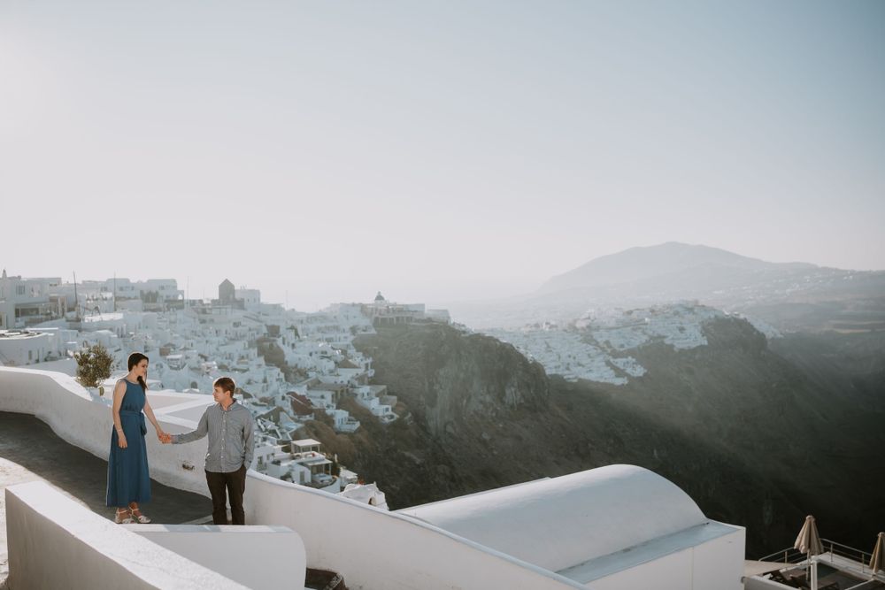Scenic view of white buildings cascading down hillside in Santorini during sunset.