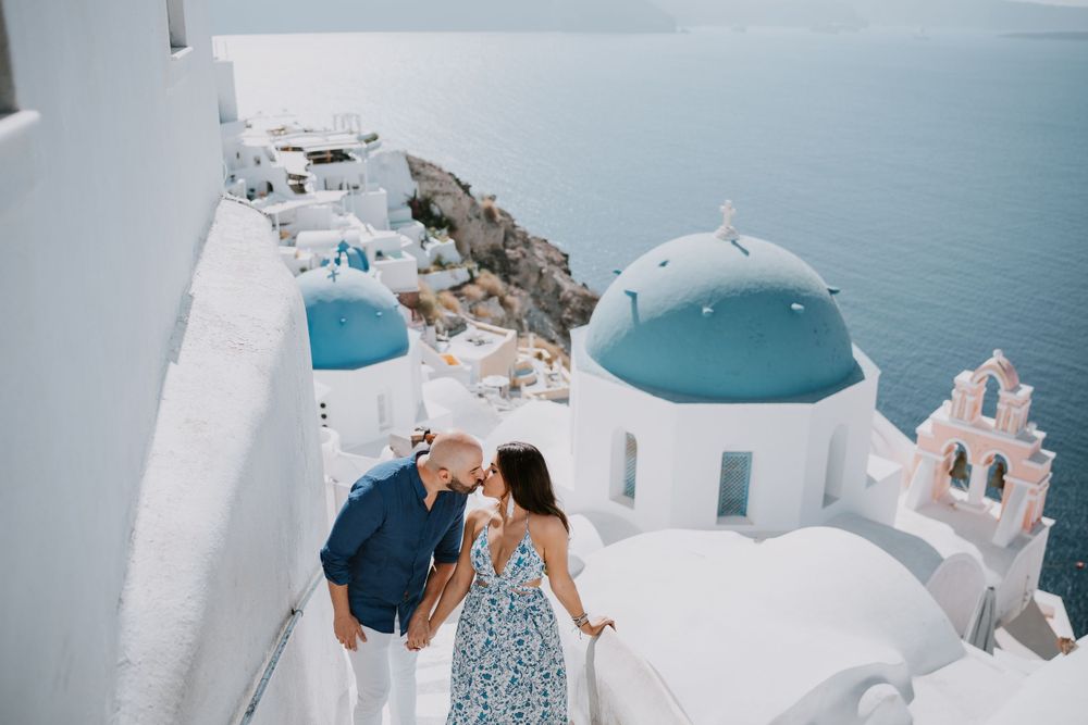 A couple shares an intimate moment overlooking Santorini's iconic blue domed churches.