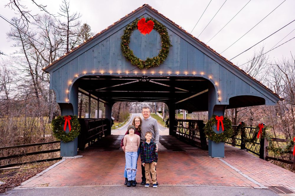 A festive covered bridge decorated with Christmas wreaths and lights during the holiday season.