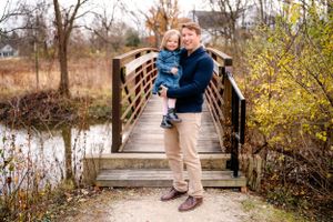 A parent and child share a moment together on a wooden footbridge.