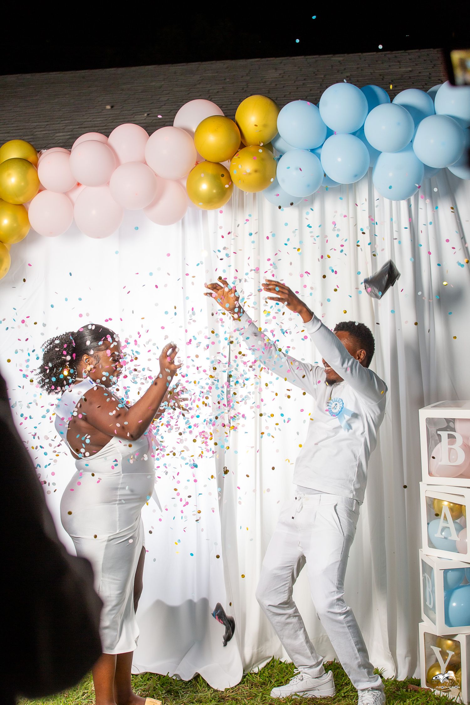 Celebratory moment with confetti and pastel balloon arch during wedding photoshoot.