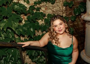 Artistic portrait against a wall with green ivy creating a natural backdrop.