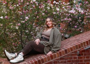 Casual portrait on brick ledge with blooming magnolia trees in background.