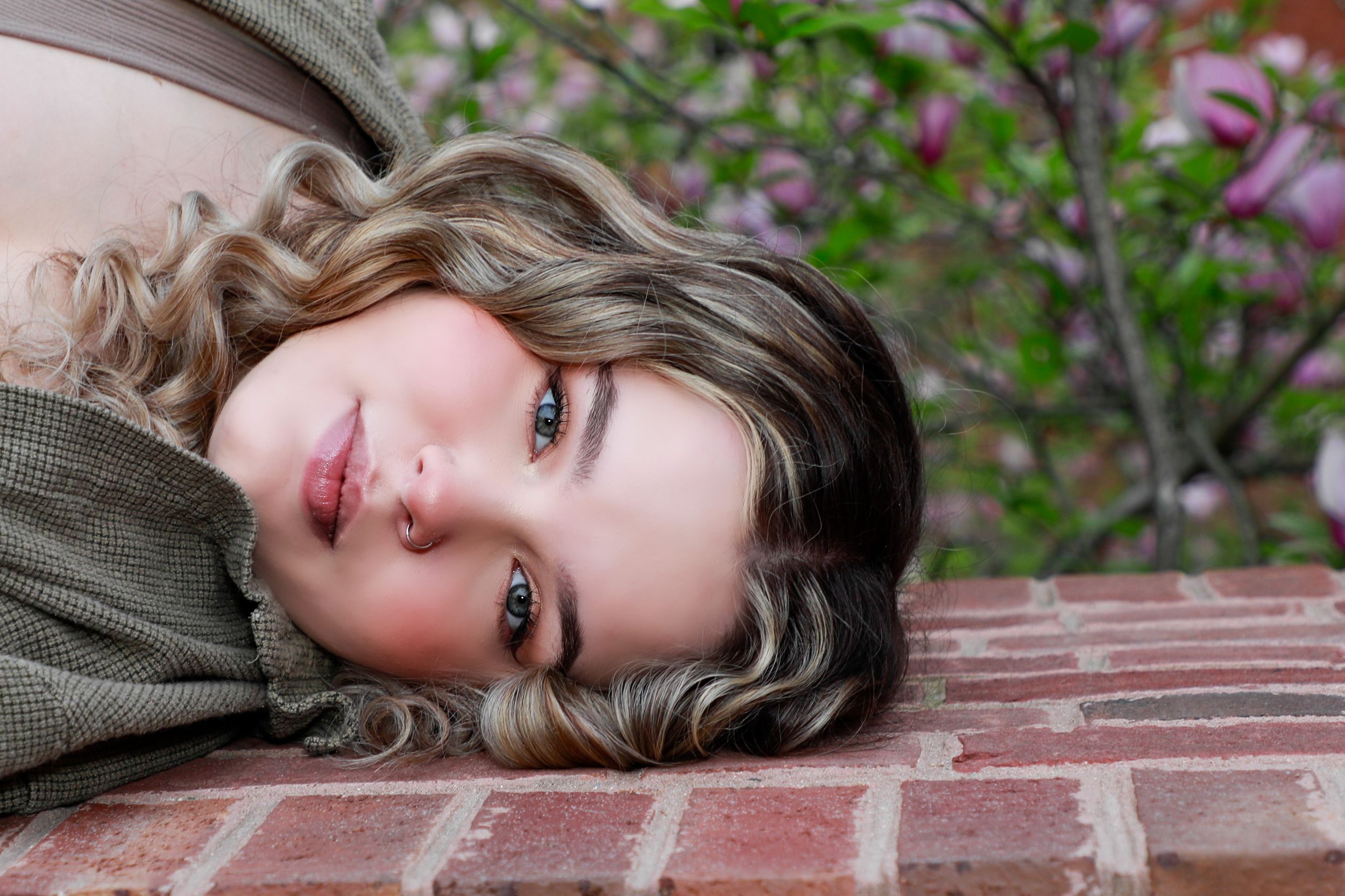 Close-up portrait laying on brick surface with purple flowers in background.