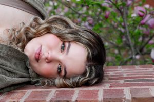 Close-up portrait laying on brick surface with purple flowers in background.