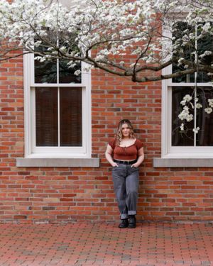 Spring portrait against brick wall with blooming cherry blossoms and white-trimmed windows.