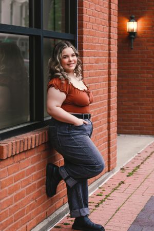 Urban fashion photography along a brick building with decorative lighting.