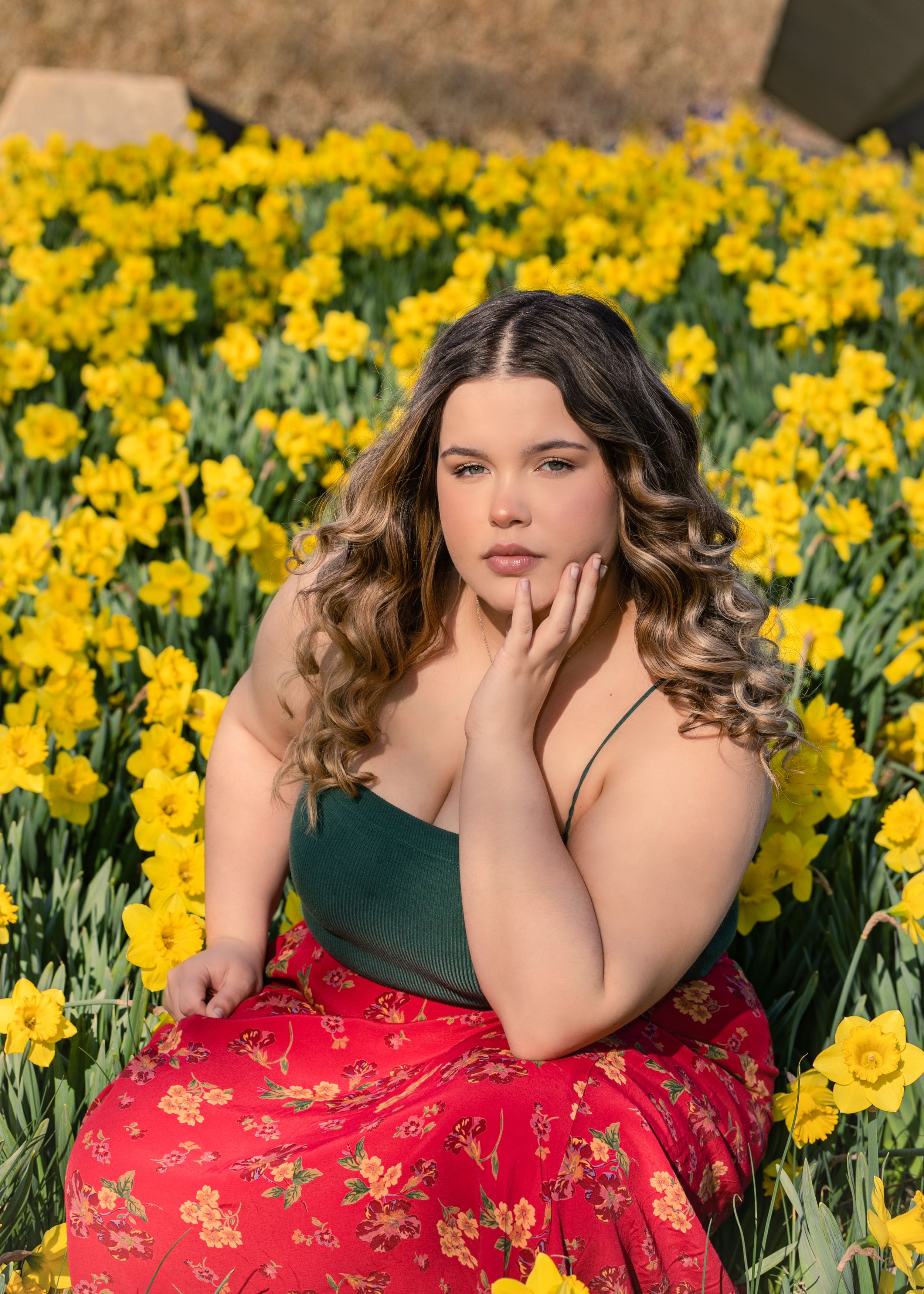Spring portrait in a blooming daffodil field with red floral dress.