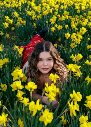 Natural outdoor photography session surrounded by bright yellow daffodil flowers.