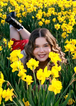 Spring portrait amidst a vibrant field of blooming yellow daffodils.