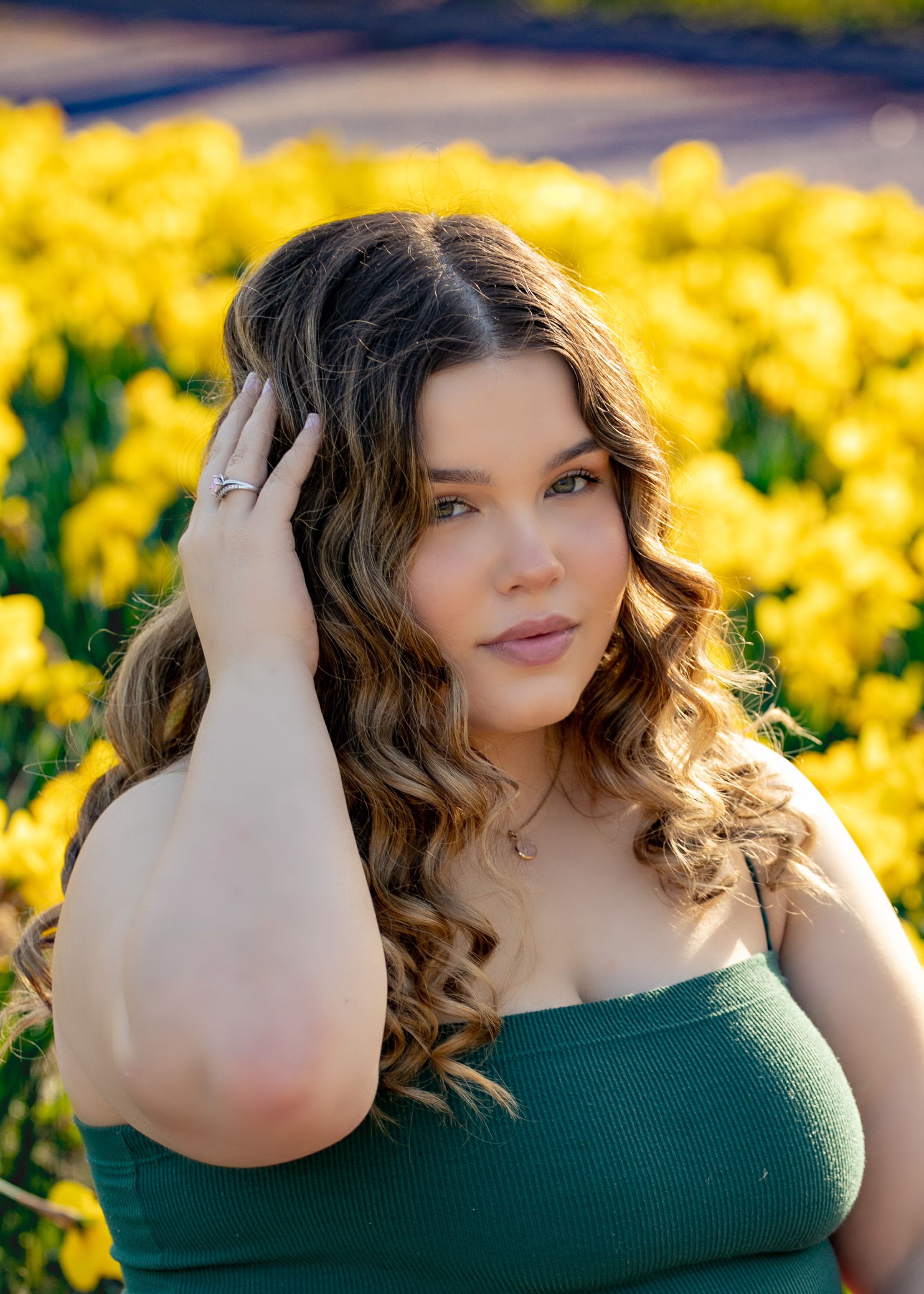 Portrait in a green top against vibrant yellow daffodils in a spring garden setting.