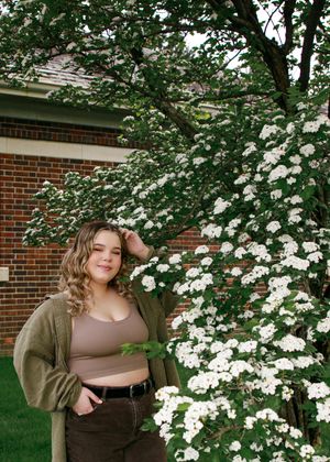 Spring portrait session with flowering dogwood trees and brick building backdrop.