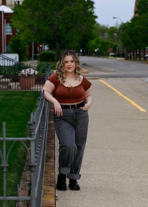 Casual outdoor photo shoot on a concrete path with brick building in background.
