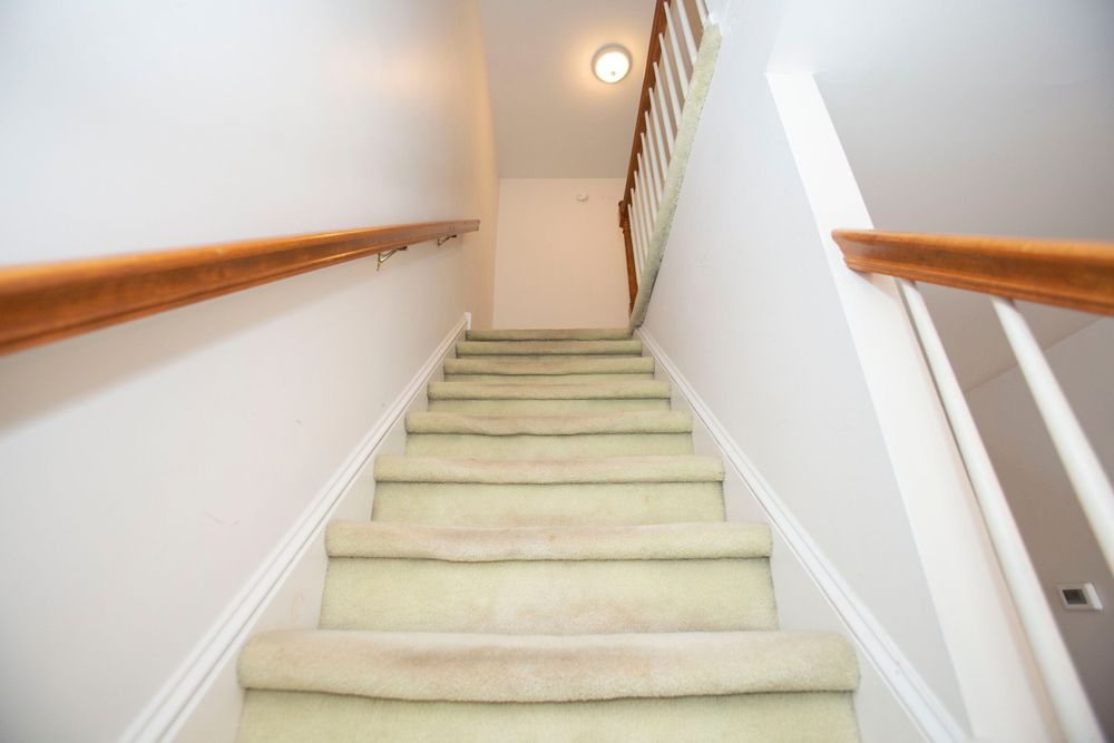 Carpeted staircase with wooden handrails leading upstairs in a residential home.
