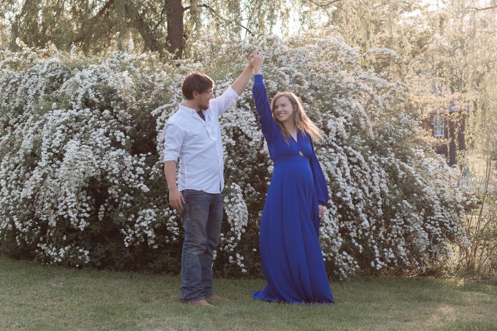 Couple dancing together near blooming white spring flowers in garden setting.