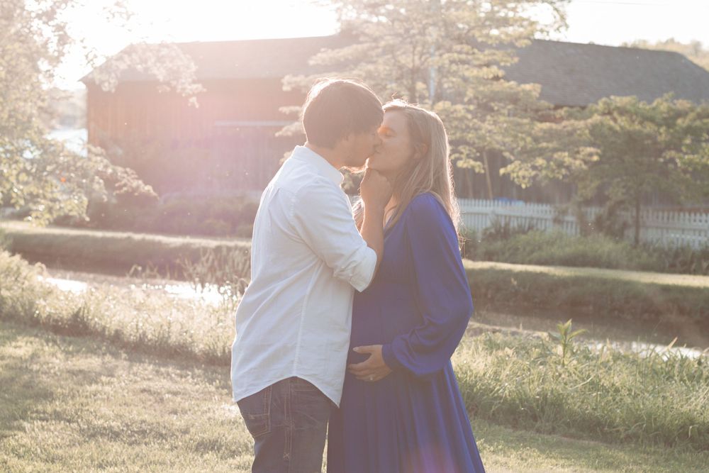 Romantic sunset maternity photo with couple in casual attire.