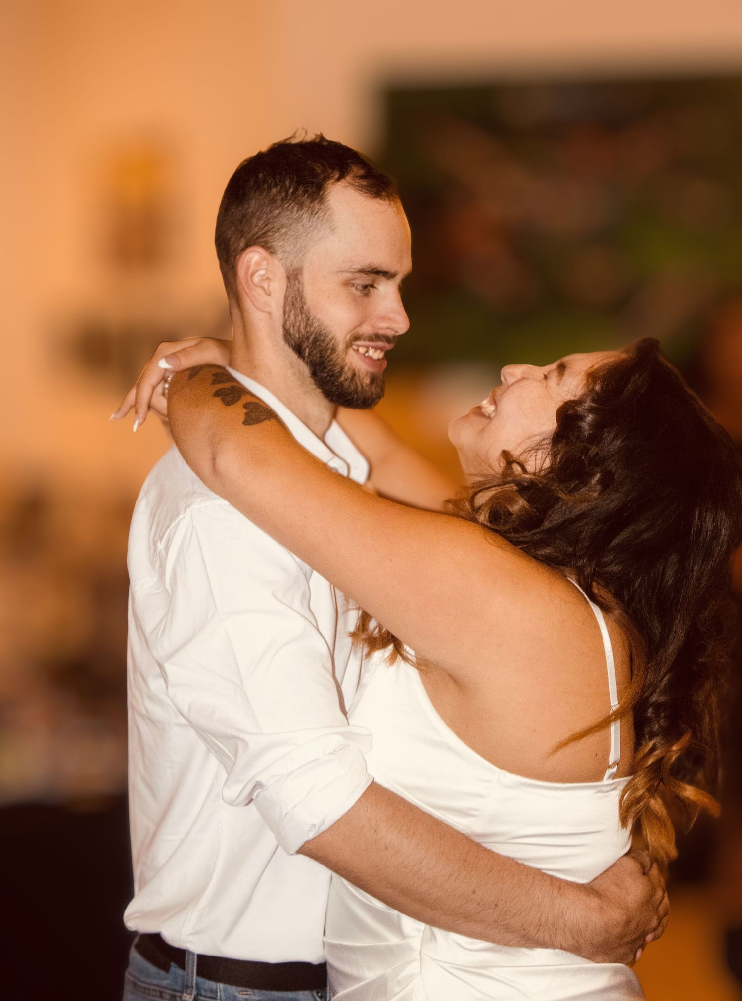 Couple shares intimate first dance, embracing closely with warm romantic lighting at wedding reception.