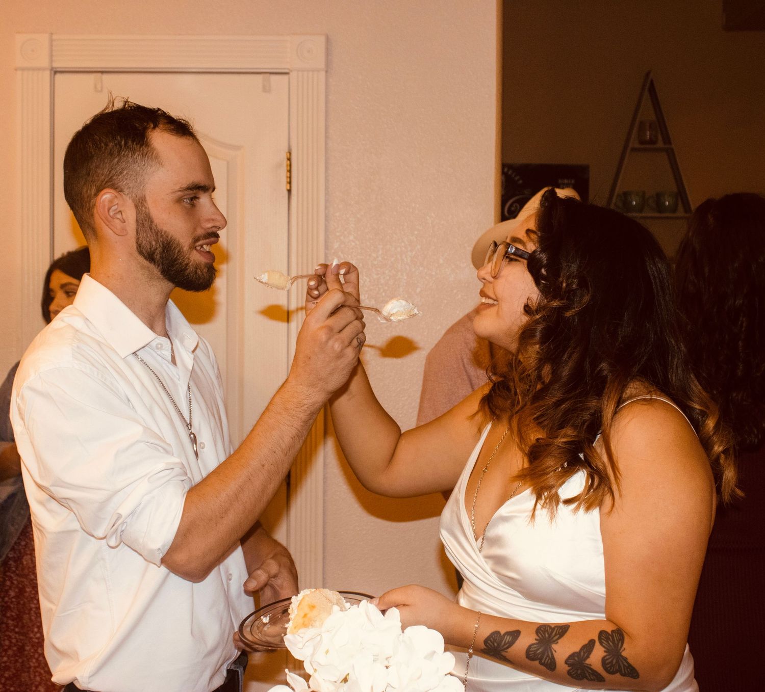 Newlywed couple shares a joyful cake feeding moment during their intimate wedding reception.