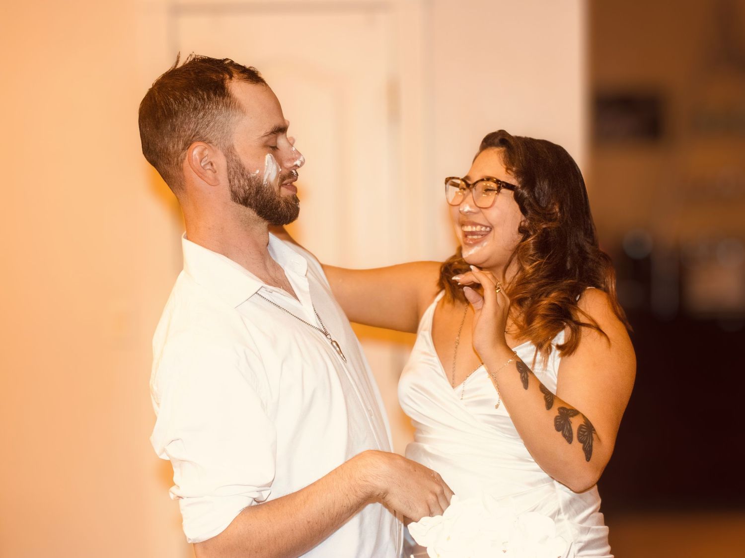 Smiling bride with glasses and groom share a joyful moment during wedding reception dance.