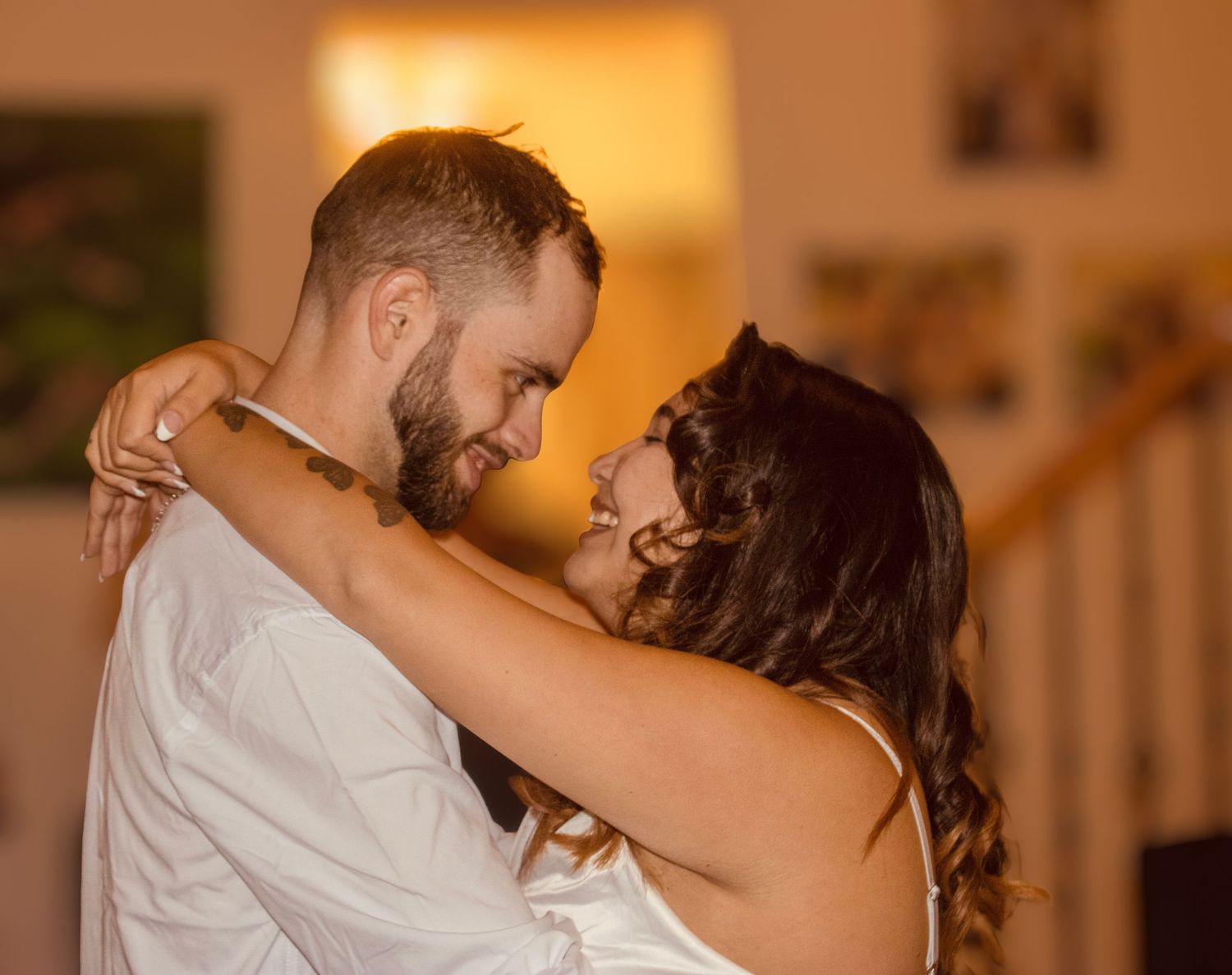 Newlyweds share an intimate first dance embrace indoors at their wedding reception.