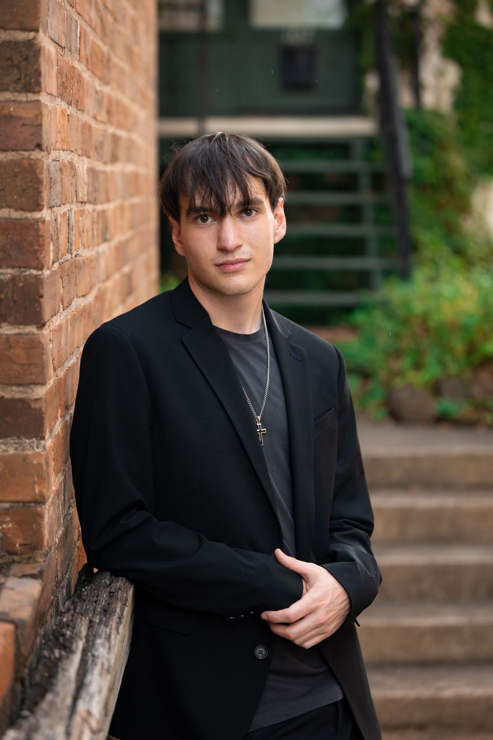 Professional portrait of a person in a dark blazer against a brick wall.
