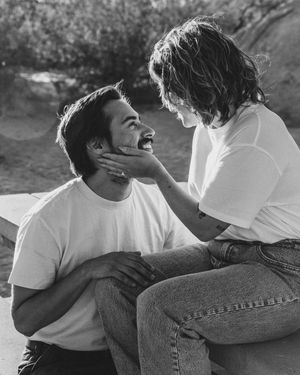 A tender black and white moment between a couple wearing white t-shirts and jeans sitting outdoors in North Carolina.