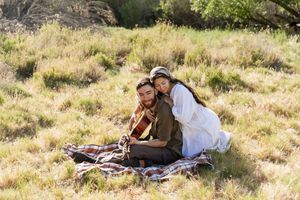 Couple having romantic picnic with guitar on sunny hillside meadow, eastern nc photographer